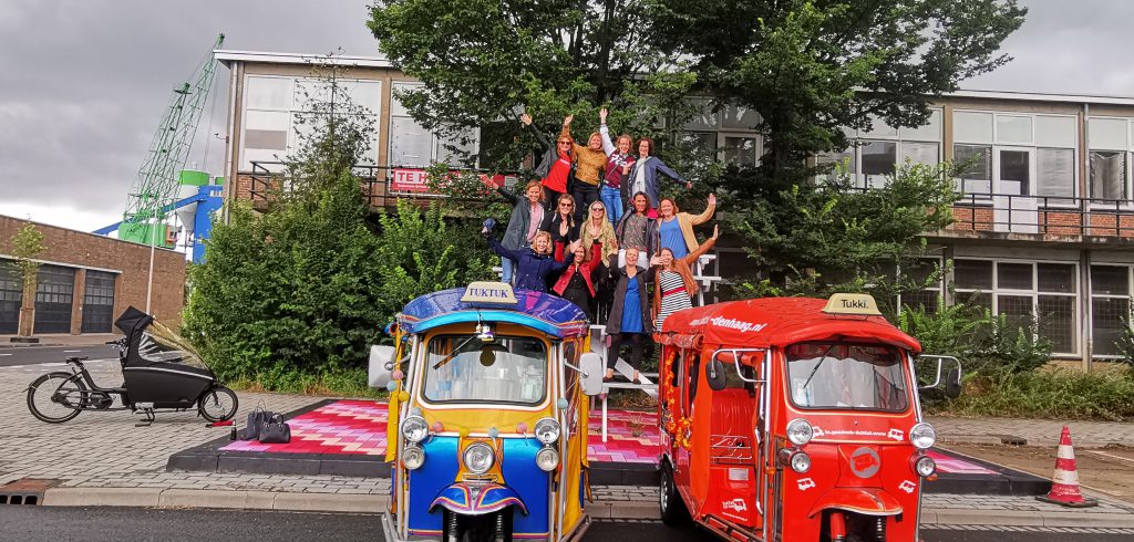 Vrolijke groep bij twee kleurrijke tuk tuks tijdens een fun ride in Den Haag