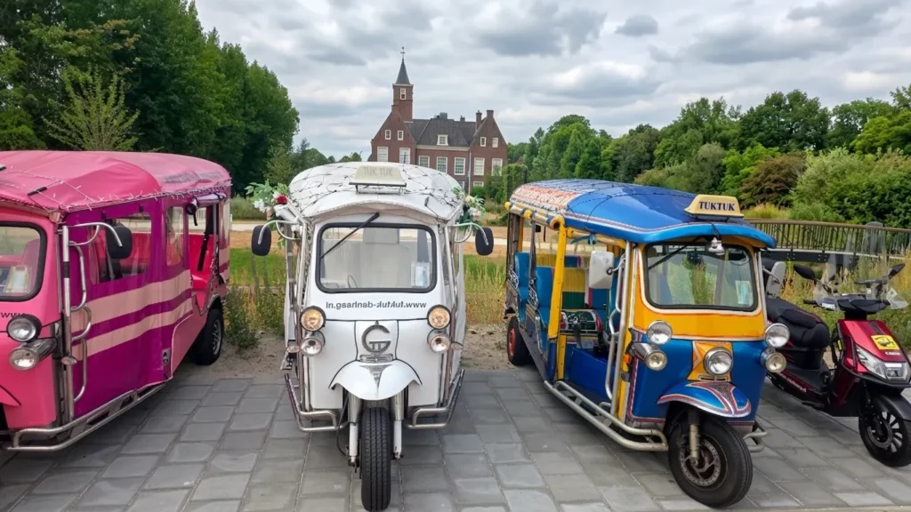 Drie kleurrijke Tuk Tuks en de nieuwe rode Tukkie scooter geparkeerd op een startplaats in de regio Den Haag.