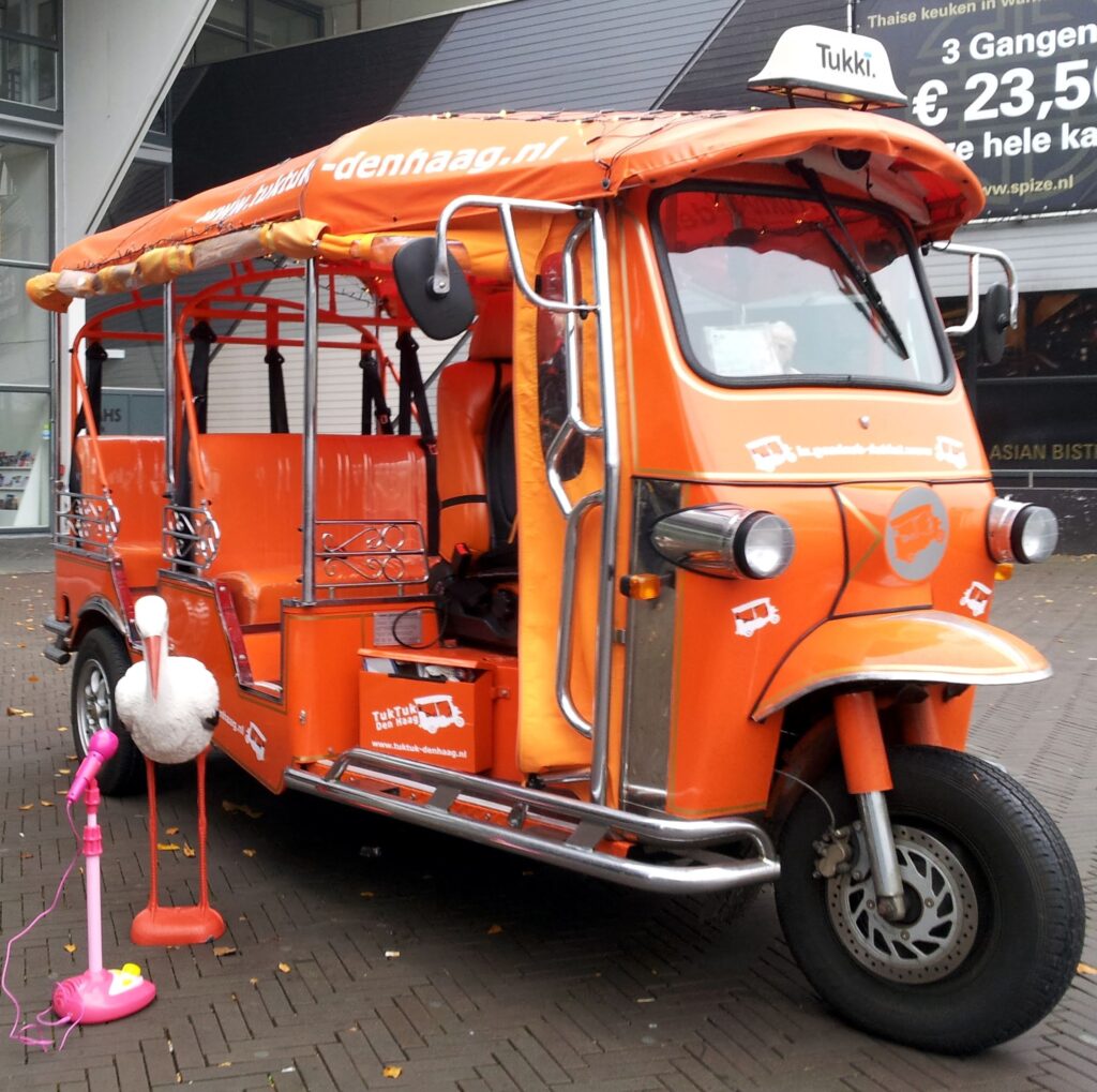 Tuk tuk huren in Den Haag: oranje tuk tuk met de ooievaar ervoor