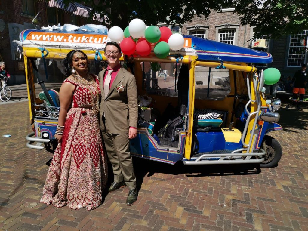 Bruidspaar bij een kleurrijke tuktuk met ballonnen in het centrum van Den Haag