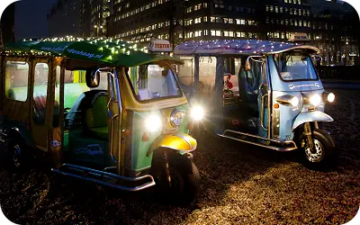 Festively lit tuk tuks during an evening ride in The Hague