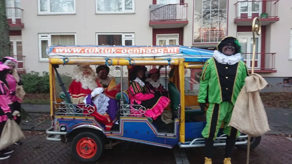 Nikolaus und Helfer mit Kindern in einem geschmückten Tuk-Tuk in Den Haag