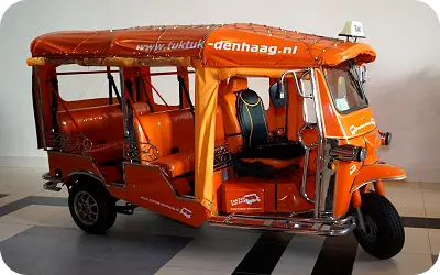 Leuchtend oranges Thai-Tuk-Tuk von TukTuk-DenHaag für eine Spaßfahrt