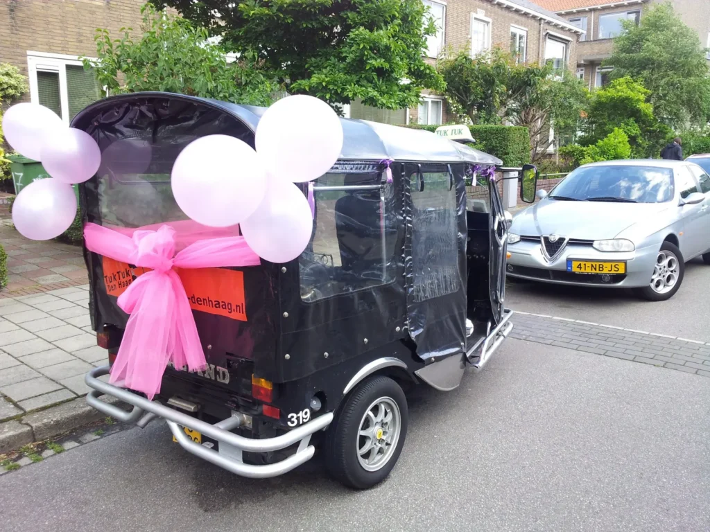 Schwarzes Tuk-Tuk mit weißen und rosa Luftballons für eine Feier