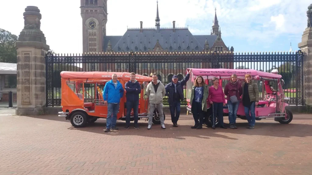 Group of visitors with the tuk tuk in front of the Peace Palace in The Hague