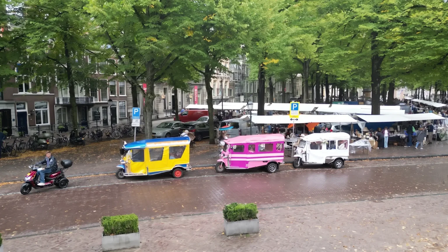 Drie kleurrijke Thaise tuktuks geparkeerd bij de markt op het Lange Voorhout in Den Haag.