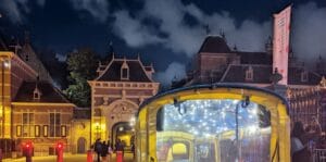 Yellow tuk tuk with fairy lights at the illuminated Stadhouderspoort gate of the Binnenhof in The Hague at night