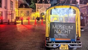 Gelbes Tuk-Tuk am Abend vor dem beleuchteten Binnenhof in Den Haag