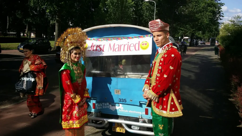 Bridal couple in traditional dress beside the tuk tuk with a Just Married sign in The Hague