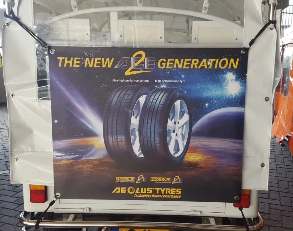 Tuk tuk with an Aeolus Tyres company banner