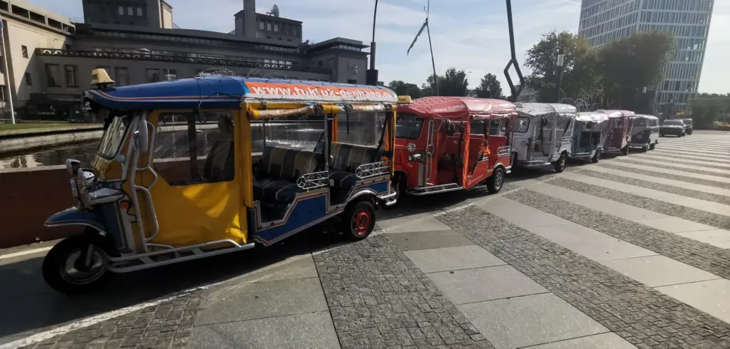 Zeven tuk tuks op een rij voor een grote groep in Den Haag