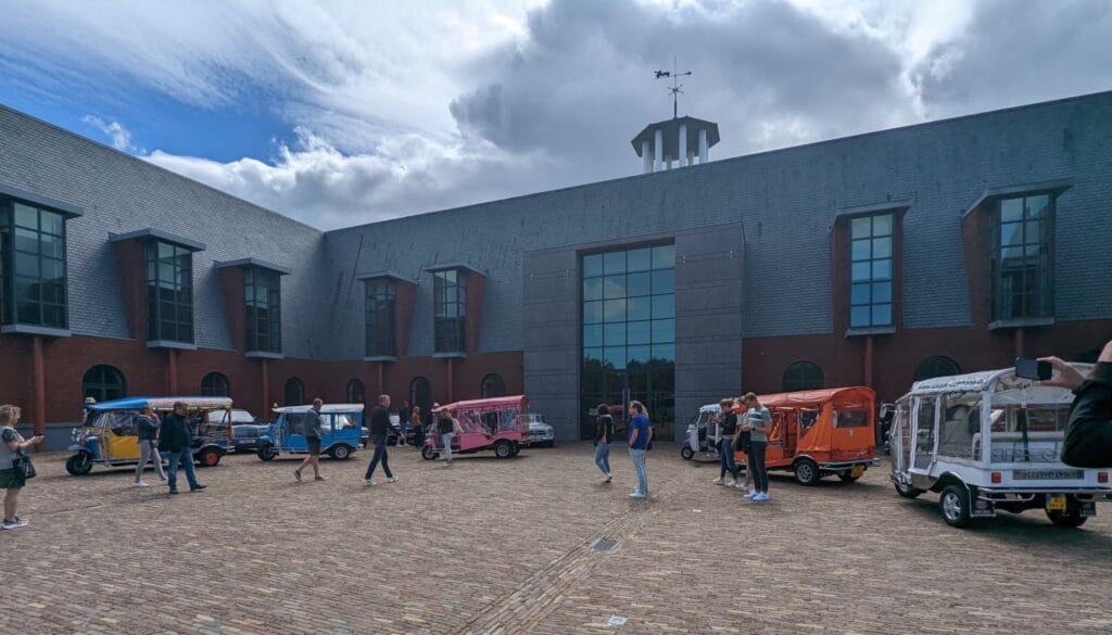 Kleurrijke Thaise tuk tuks met gasten op een binnenplein, klaar voor Park+Ride in Den Haag