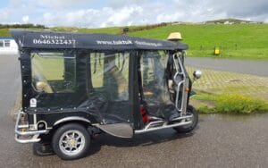 Zwarte tuk tuk van Tuk Tuk Den Haag met de naam en het telefoonnummer van Michel op het dak